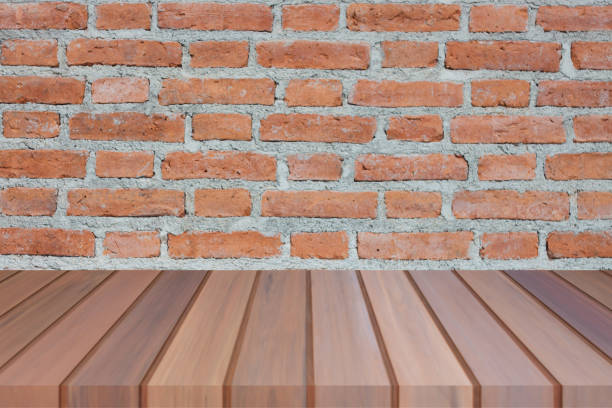 istock Brown wooden table top on brick wall 1027966526