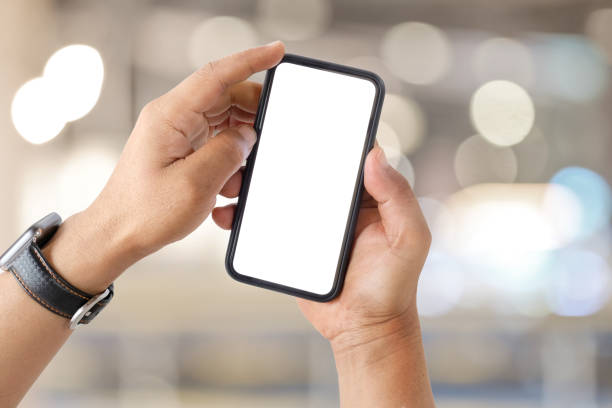 istock Man's hand shows mobile smartphone with white screen over blurred background. 1027968912