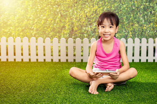 Asian Little Chinese girl playing with mobile phone at outdoor park