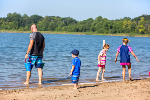istock Father & Three Young Children Playing at Beach 1027994368