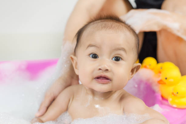 istock baby taking a bath in bathtub and playing with foam bubbles 1028005278