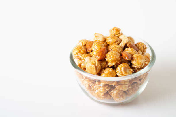 istock Caramel popcorn with cashew nuts and almonds in a white background, selective focus. 1028044760