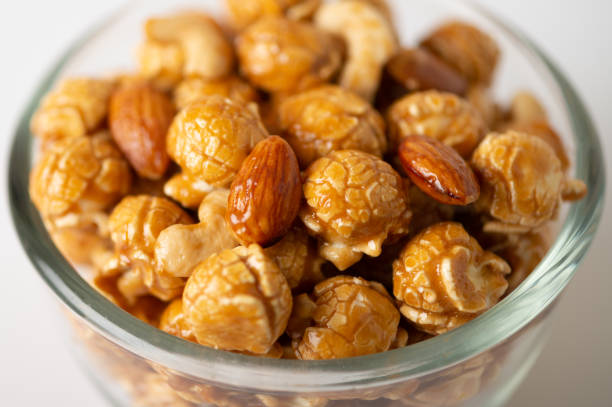 istock Caramel popcorn with cashew nuts and almonds in a white background, selective focus. 1028044766