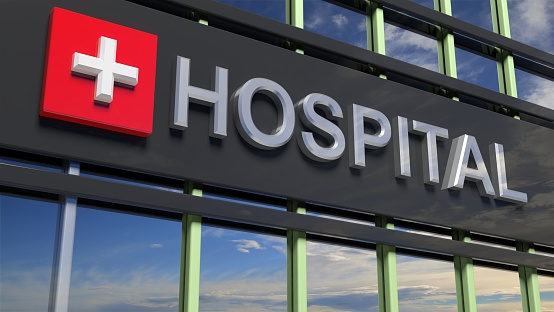 Hospital building sign closeup, with sky reflecting in the glass.