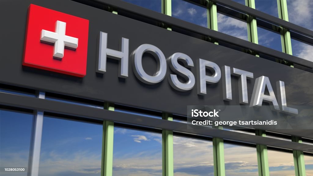 Hospital building sign closeup, with sky reflecting in the glass. Hospital Stock Photo