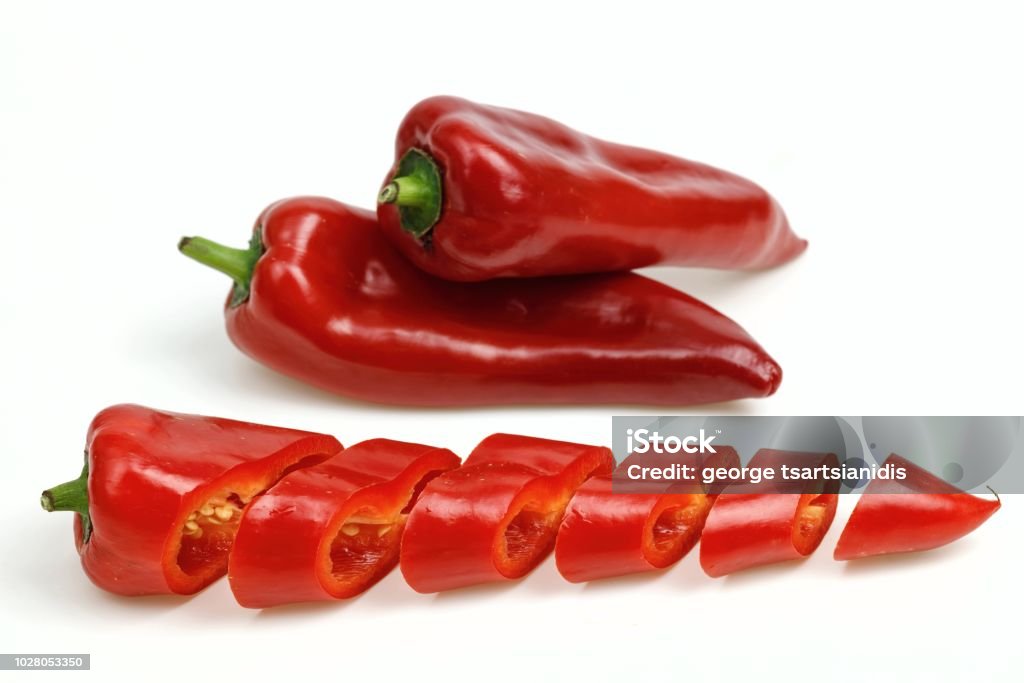 Pointy red peppers and one cut into pieces, on white background. Greece Stock Photo