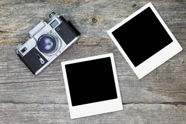 istock Old analog camera with blank photo frames, on wooden surface 1028053918