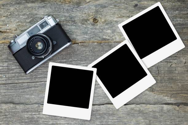 istock Old analog camera with blank photo frames, on wooden surface 1028053920
