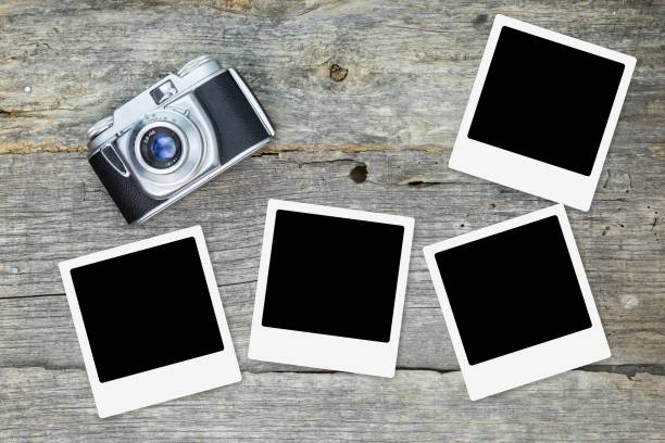 istock Old analog camera with blank photo frames, on wooden surface 1028053924