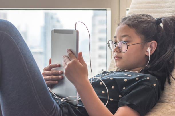 estilo de vida de la tecnología digital de niña de escuela o estudiante con internet inalámbrico a distancia aprendizaje aplicación y lectura de e-book app en ipad móvil dispositivo inteligente multimedia computadora de la tableta - lector de libros electrónicos fotografías e imágenes de stock