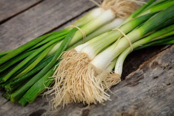 Green scallions heaps, on wooden surface