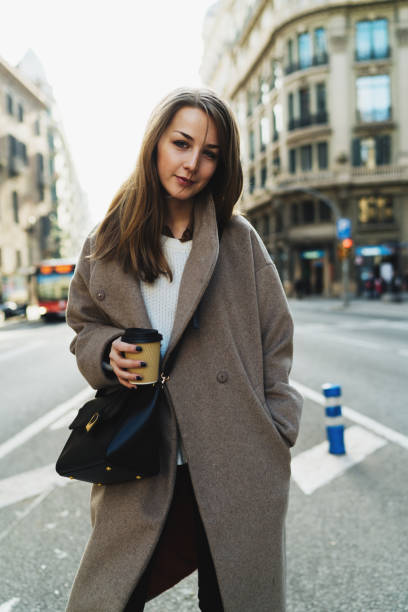 istock Smiley female manager getting to work by feet drinking morning coffee to go while walking street. Successful business woman in trendy wear enjoying sunny weather strolling around the city 1028091890