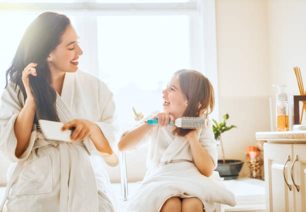 istock Mother and daughter combing hair 1028095884