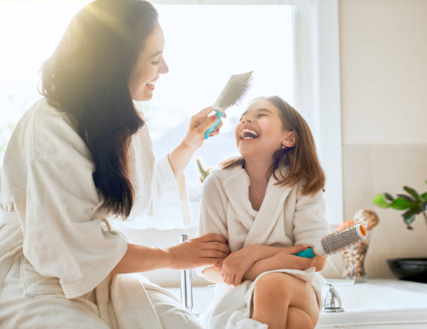 istock Mother and daughter combing hair 1028095914