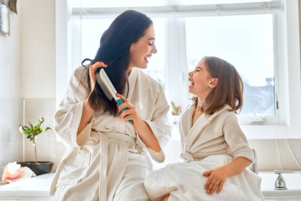 istock Mother and daughter combing hair 1028095924