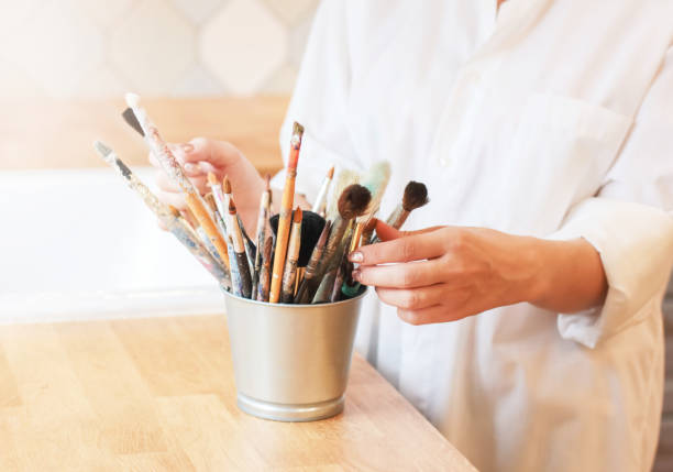 istock Different brushes in metal bucket with artist hands, selective focus 1028104356
