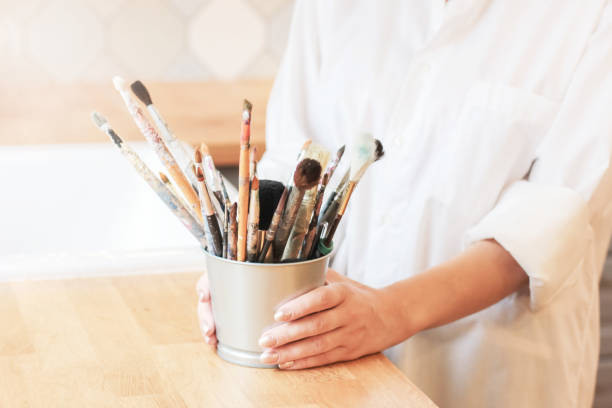 istock Different brushes in metal bucket with artist hands, selective focus 1028104424