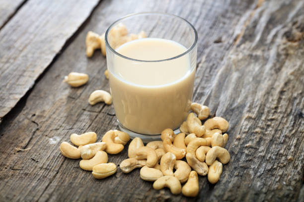 Heap of raw cashews and a glass of cashew milk, on wooden surface Heap of raw cashews and a glass of cashew milk, on wooden surface cashew photos stock pictures, royalty-free photos & images