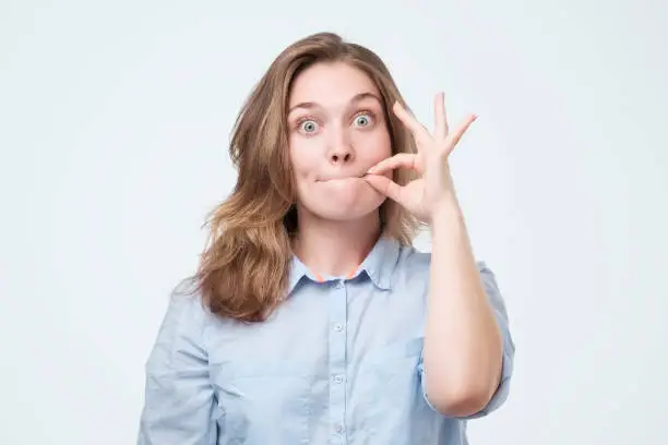 Photo of Woman zipping her mouth shut - keeping quiet concept