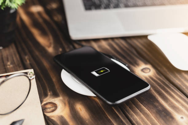 close-up phone charging on wireless charger device close-up phone charging on wireless charger device battery charger photos stock pictures, royalty-free photos & images