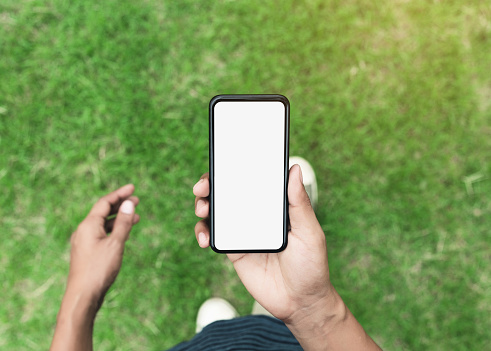 man holding phone showing blank screen walking on lawn