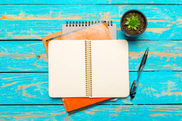 Top view workspace with blank notebook and pen on wooden table background