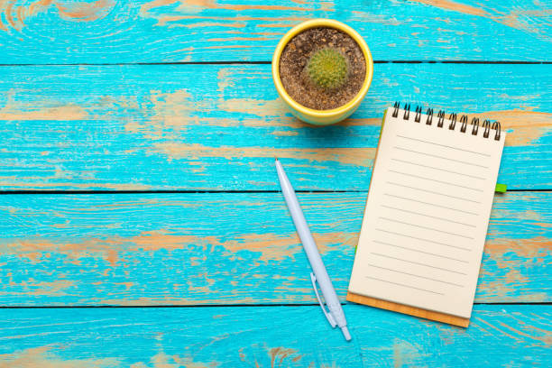 istock Top view workspace with blank notebook and pen on wooden table background 1028120006