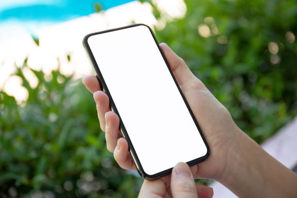 istock female hands holding phone with isolated screen on garden background 1028120220