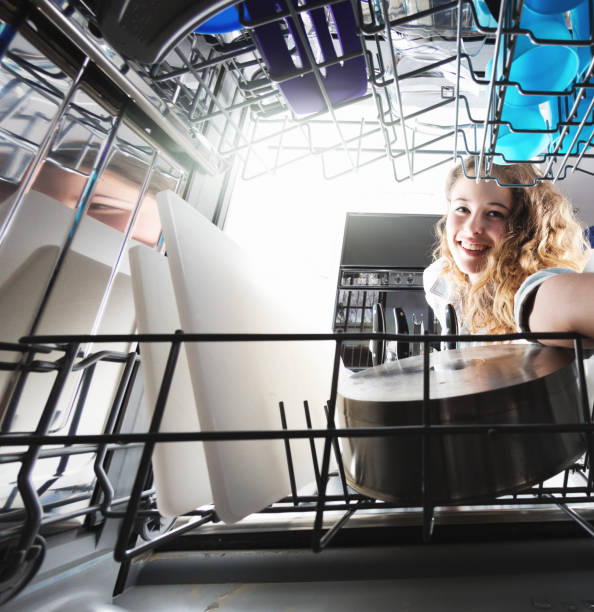 istock Beautiful girl reaching into dishwasher smiles 1028123204
