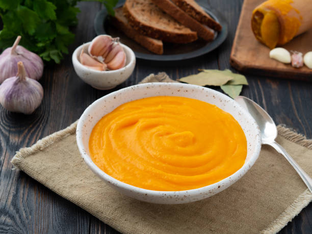 carrot puree, mashed of roasted carrot in white plate on dark wooden background, side view carrot puree, mashed of roasted carrot in white plate on a dark wooden background, side view soup lentil healthy eating dishware stock pictures, royalty-free photos & images