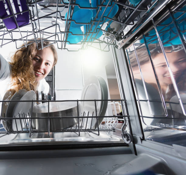 istock Pretty girl reaching into dishwasher smiles 1028127480