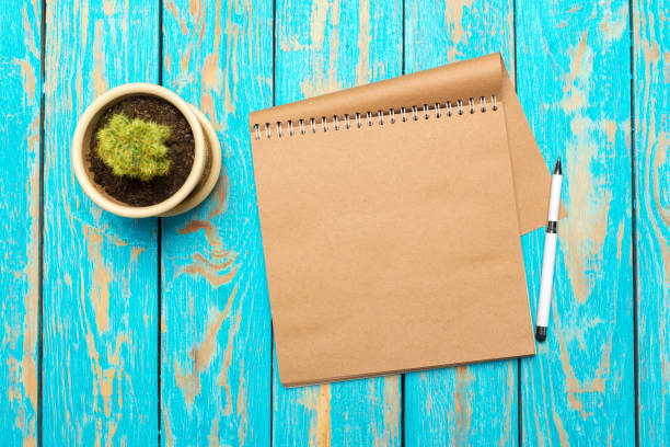 istock Top view workspace with blank notebook and pen on wooden table background 1028131508