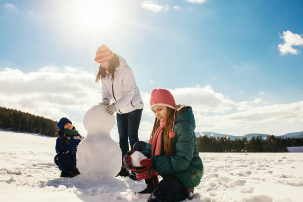 istock Mother and her children making snowman 1028134870