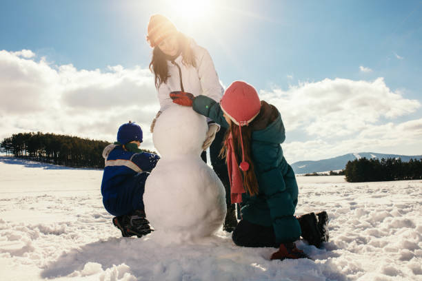 istock Mother and her children making snowman 1028134872