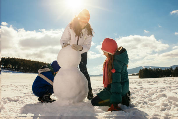 istock Mother and her children making snowman 1028134876
