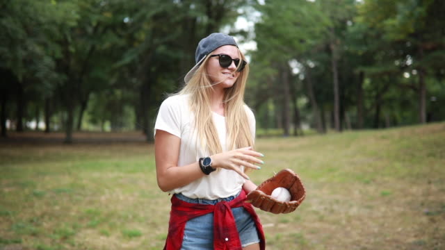 Retro looking hipster girl playing baseball in a forest