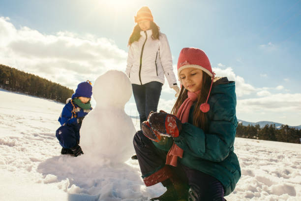 istock Mother and her children making snowman 1028135370