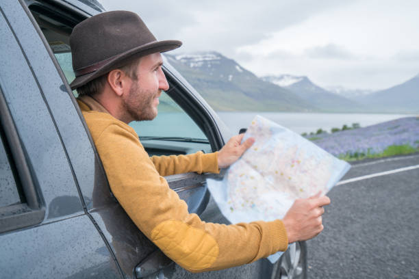 istock Young man in car looking at map, road trip concept vacations 1028138680