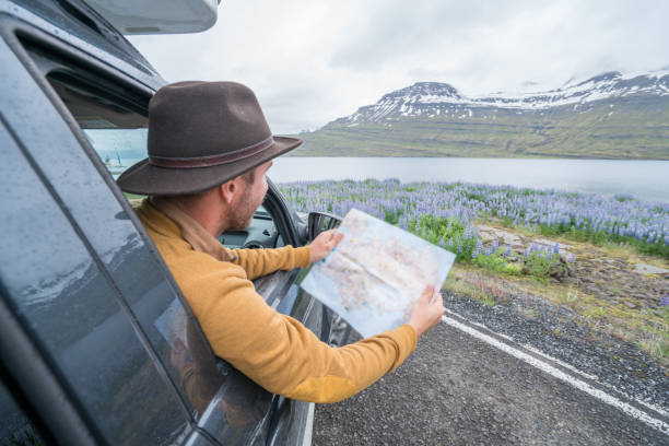 istock Young man in car looking at map, road trip concept vacations 1028138736
