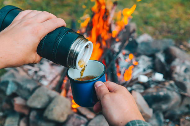 istock man pour tea in metal cup. camp fire on background 1028139970