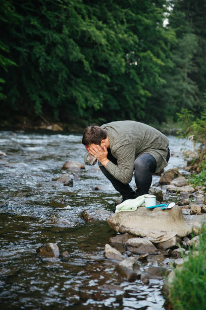 istock man wash off on riverside in mountains 1028139974