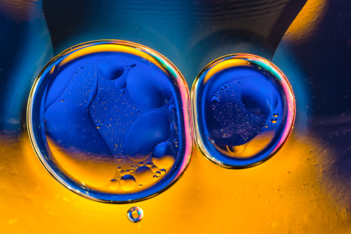 Beautiful color abstract background from mixied water and oil. Blue and orange water ripples and bubbles reflections