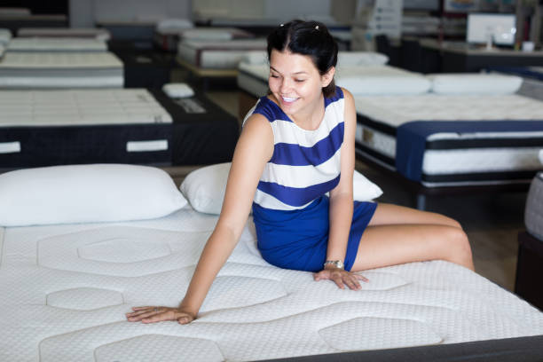 istock Customer smiling girl is sitting testing new mattress 1028155444