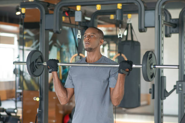 istock Black man standing and lifting barbell in gym 1028158380