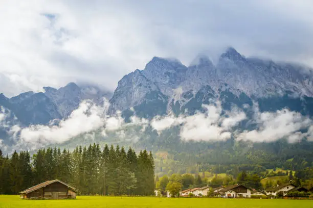 The city of Grainau, Germany with the cloudy Alps mountains in the background at summer sunlight.