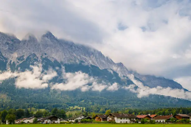 The city of Grainau, Germany with the cloudy Alps mountains in the background at summer sunlight.