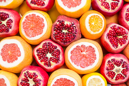 Many opened fruits at a market in Istanbul, Turkey during sunny day. Nice natural background with pomegranates, oranges and grape-fruits