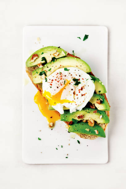 tasty sandwich with poached egg and avocado - poached egg imagens e fotografias de stock