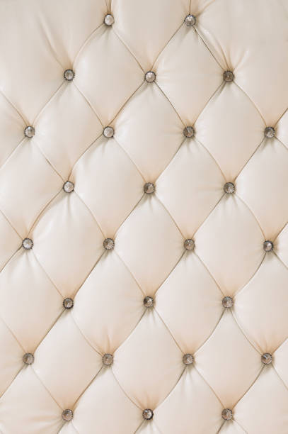 istock Beige soft tapestry pattern background with symmetrical buttons on the corners of diamonds. Soft and expensive furniture elements. Luxury background 1028187948