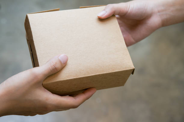 istock hands passing and receiving small brown box 1028193538